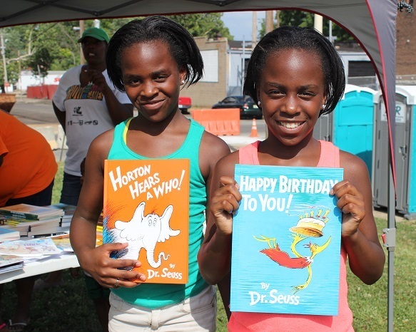 Two elementary age girls smiling at camera holding books